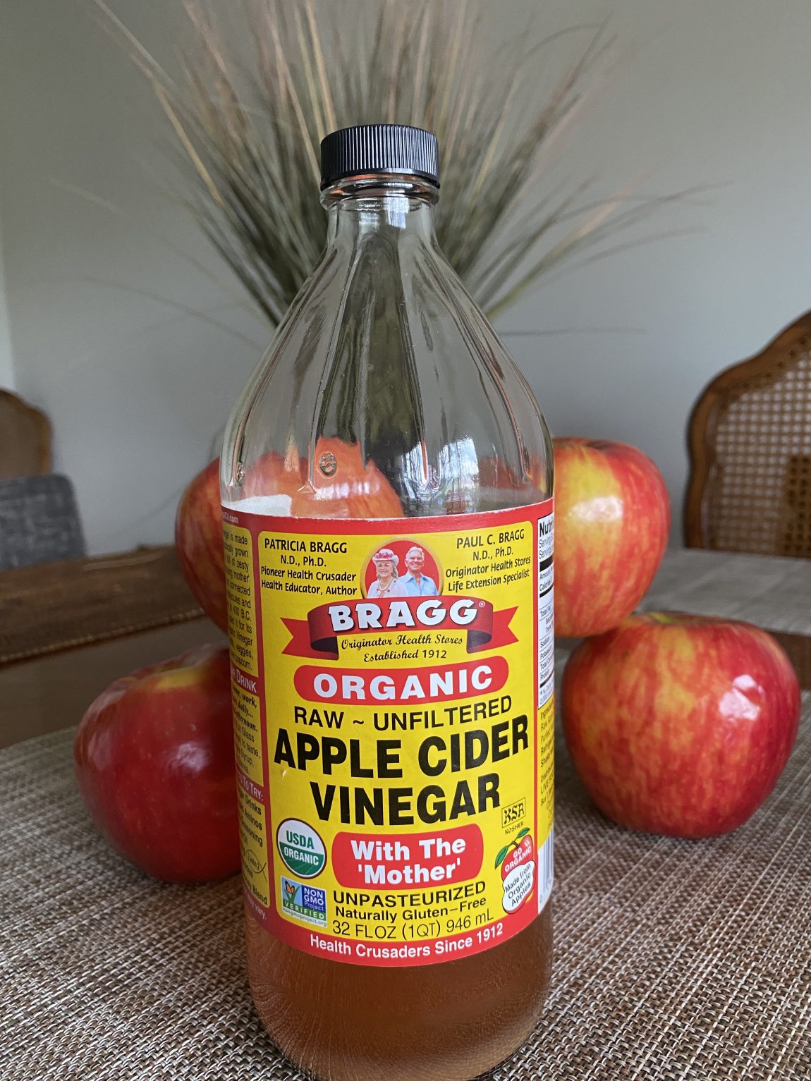 A bottle of apple cider vinegar and apples